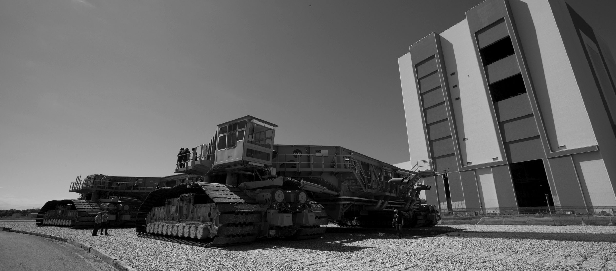 A crawler transporter moving on its tracks beside a vehicle assembly building