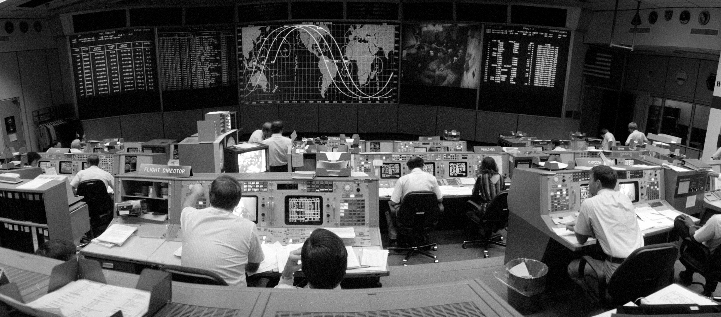 A mission control room with rows of consoles and operators